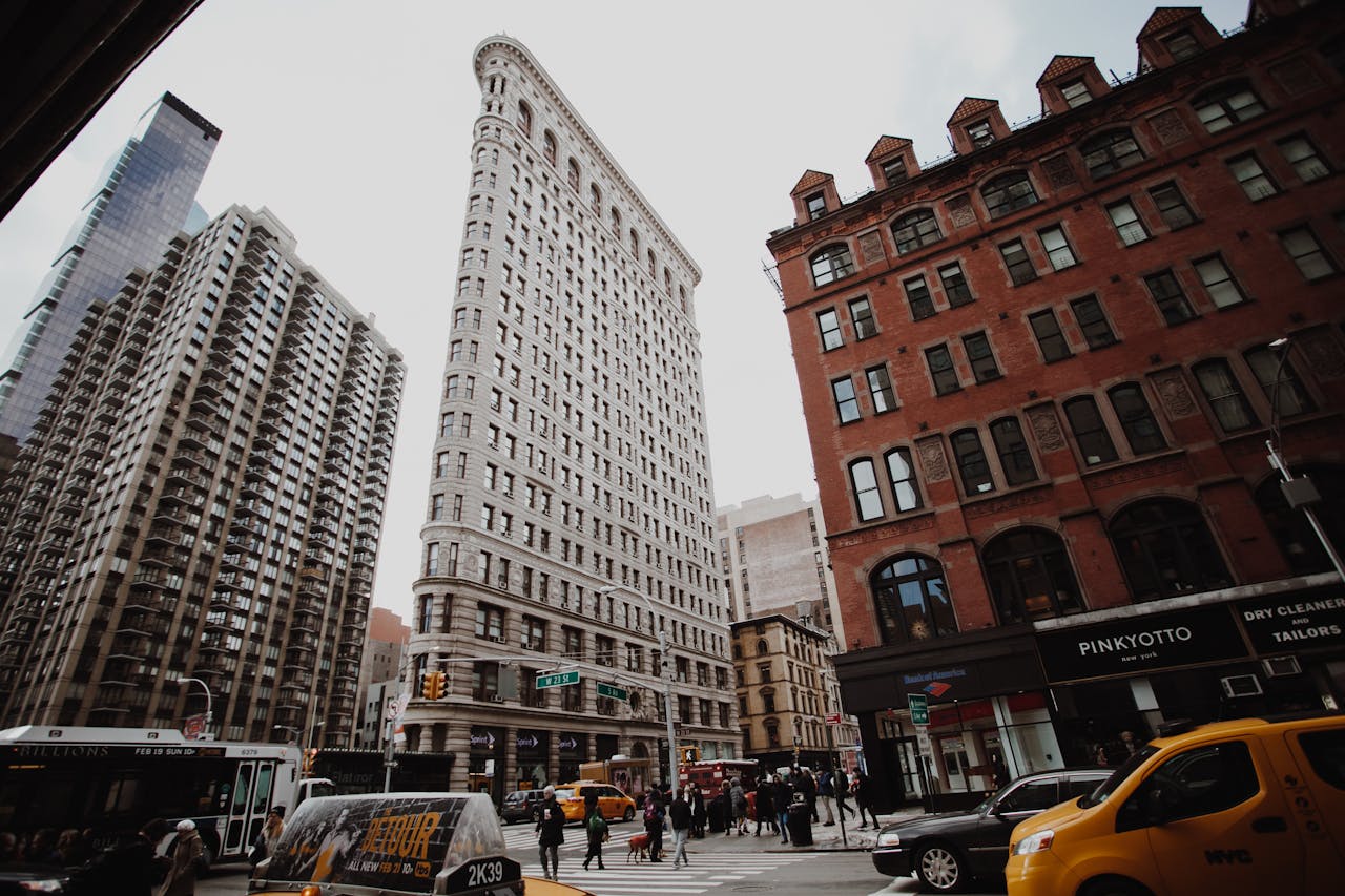 Dramatic cityscape view of New Yorks iconic Flatiron Building amidst bustling street traffic.